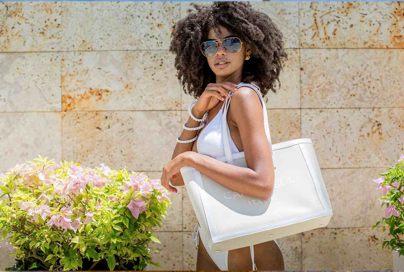Beach girl with a large tote canvas bag with matching jelly bracelets and aviator sunglasses 