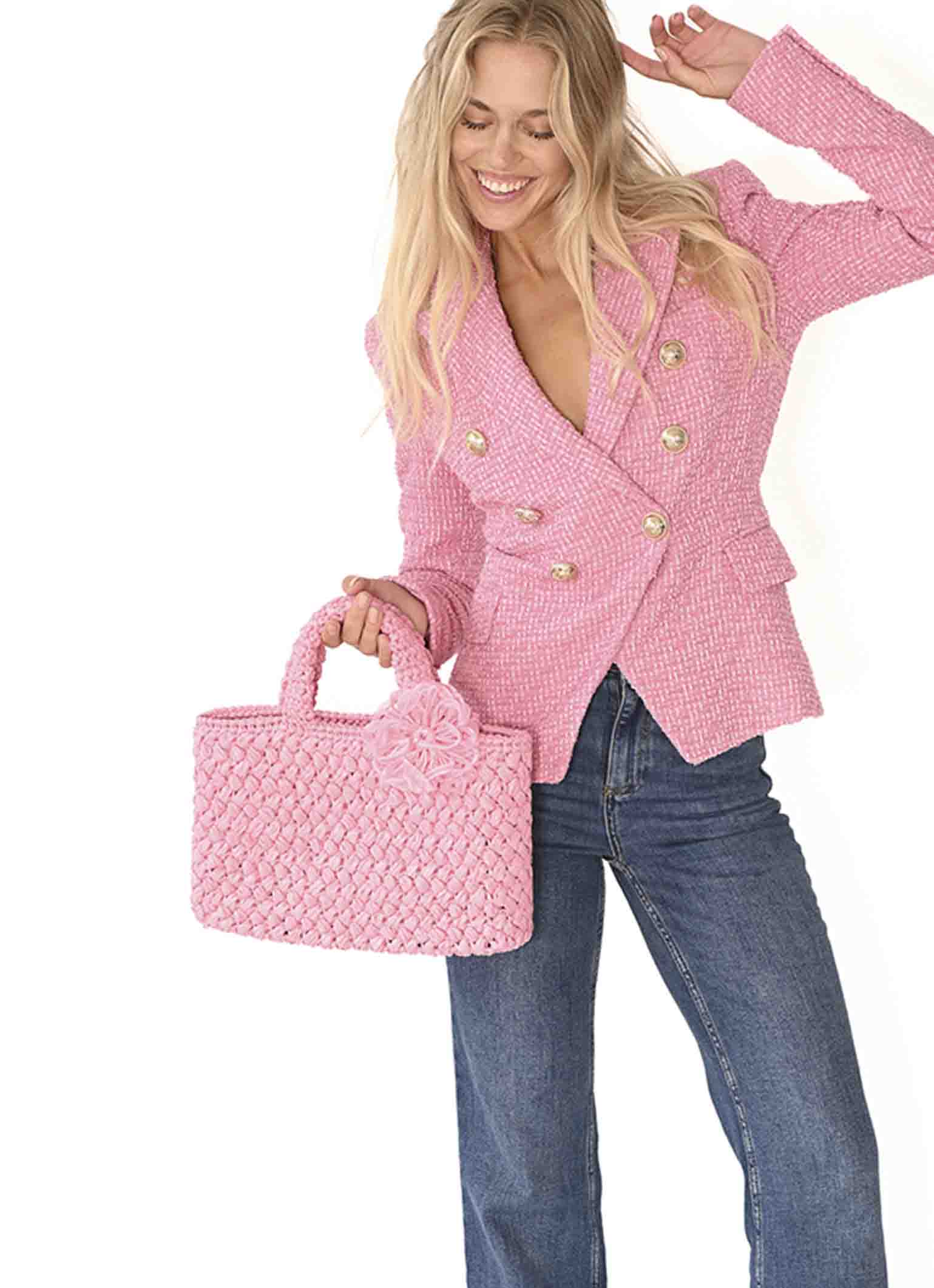 Women carries pink Positano Raffia Small Bag a chic accessory for beach lovers and avid shoppers alike from Carmen Sol.