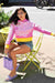 Barbie look girl seating in a park in NYC wearing jelly shoes in violet and matching jelly bag