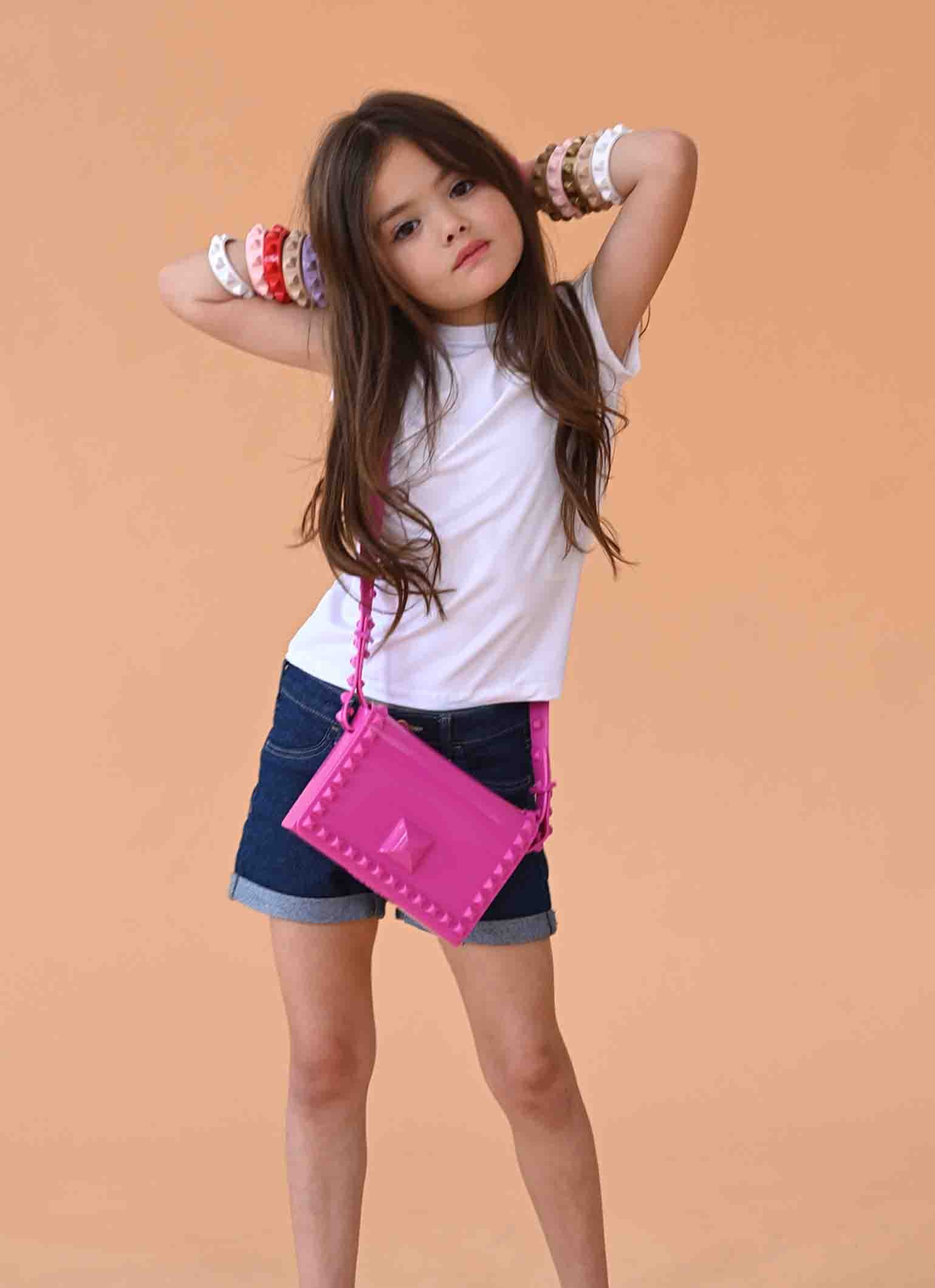 Young girl wearing colorful studded jelly bracelets and a pink purse