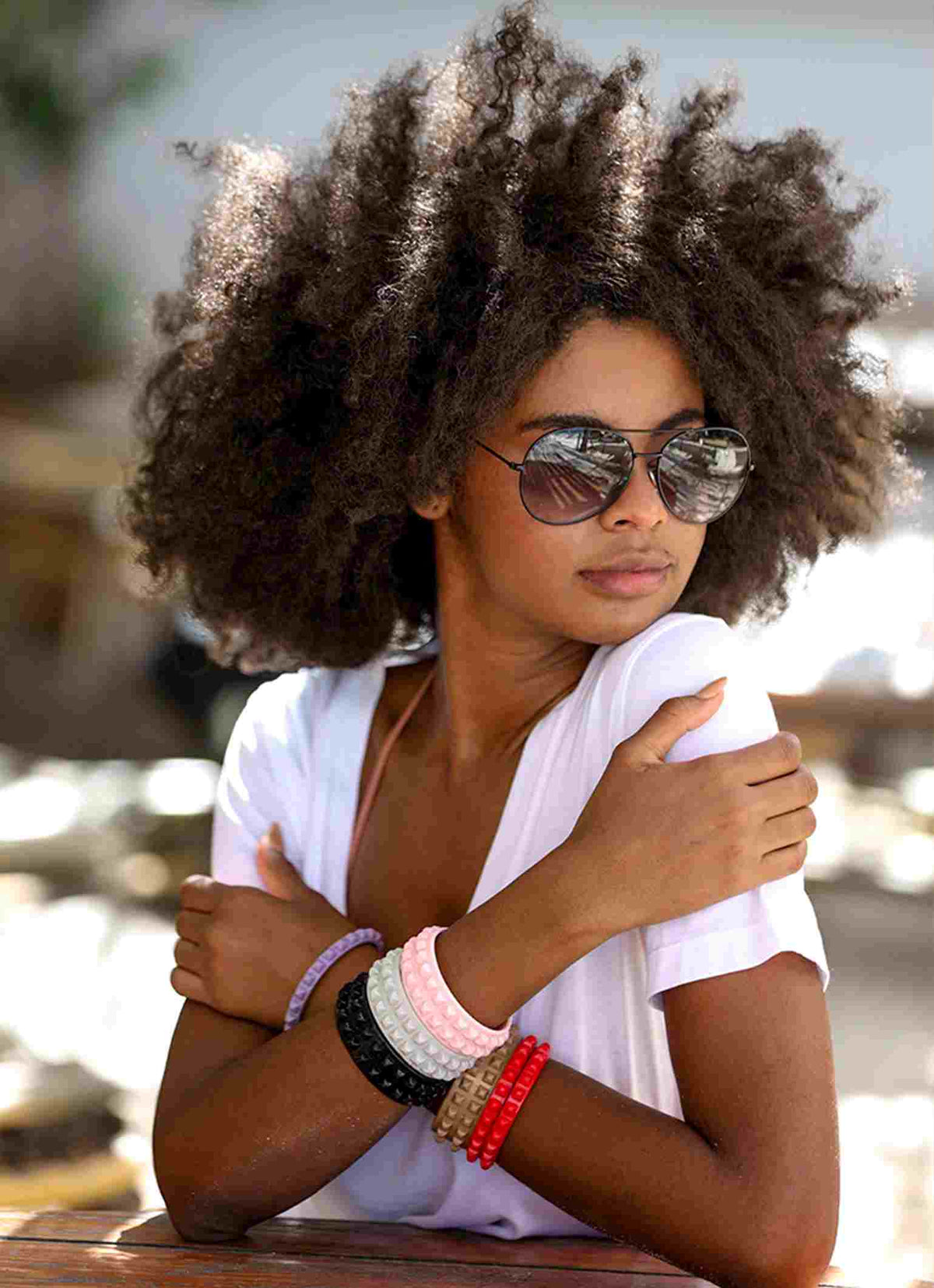 Girl wearing black sunglasses and stackable jelly bracelets on the beach