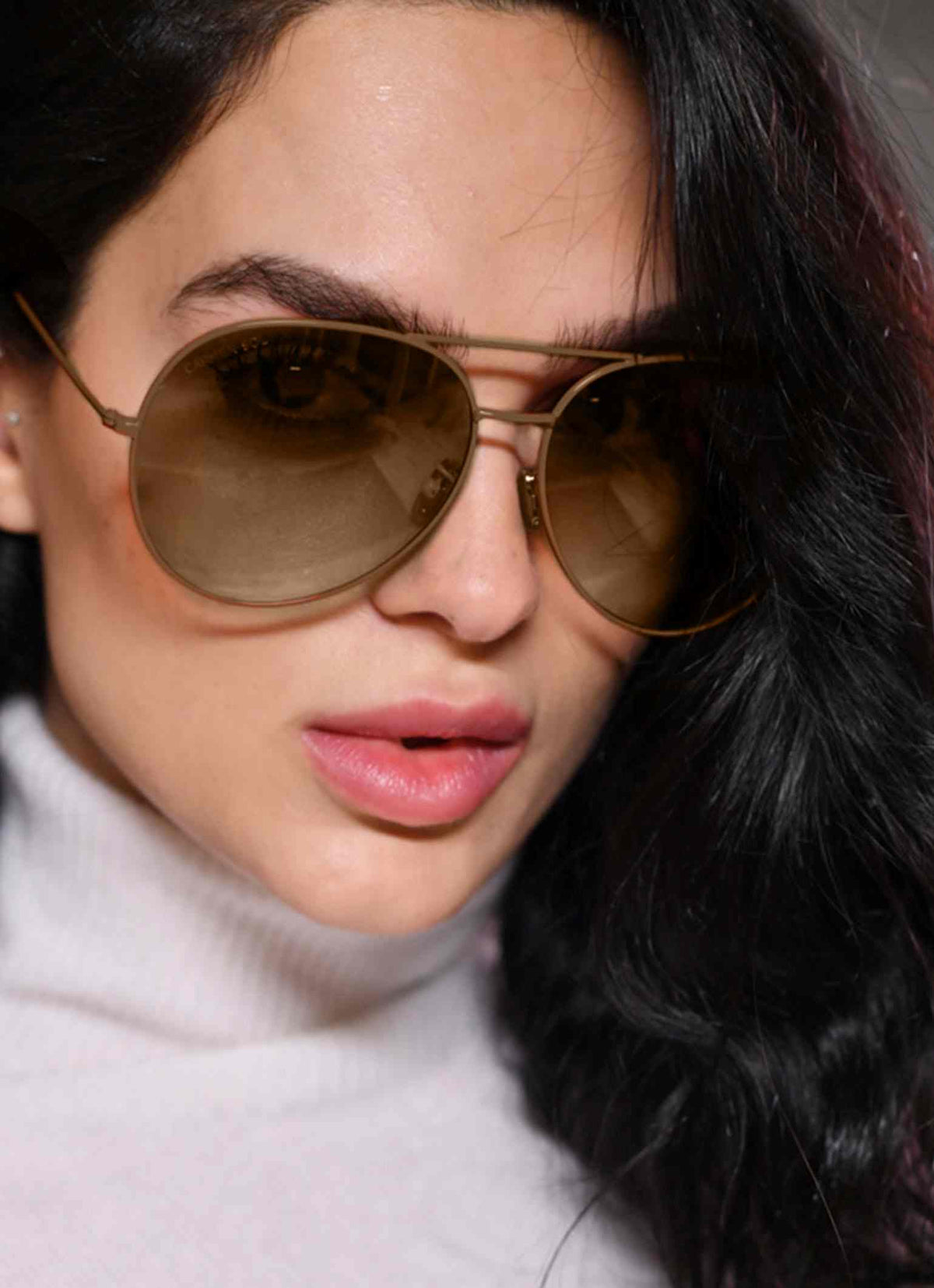Woman wearing brown aviator sunglasses and white cashmere sweater