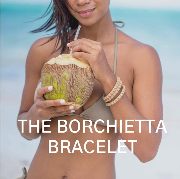 Women on the beach wearing jelly water proof bracelets stackable with a coconut water and wearing a matching color bathing suit