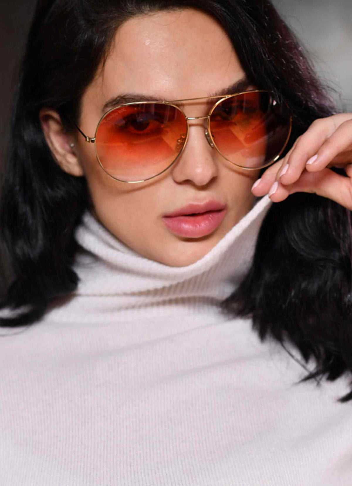 Woman wearing gold sunglasses style aviator with red lenses gradient